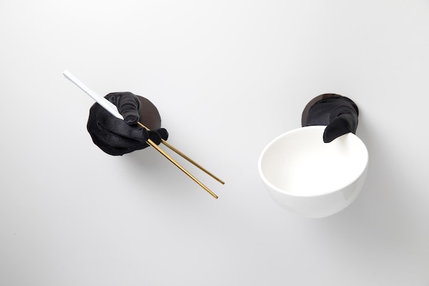 Chopstick and bowl hold with glove on white background