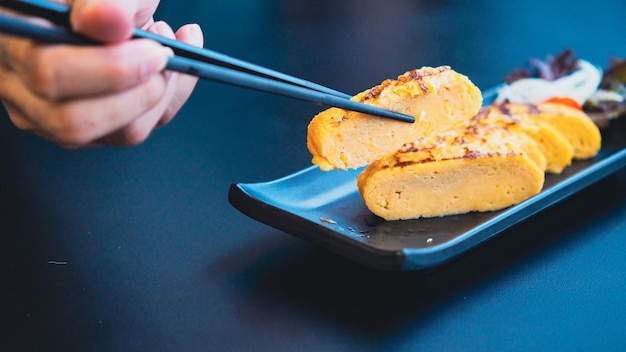 chopstick hold Tamagoyaki, Soft focus sweet omelette in Japanese