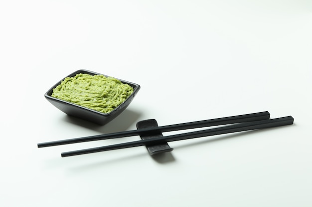 Chopsticks and wasabi sauce on white background