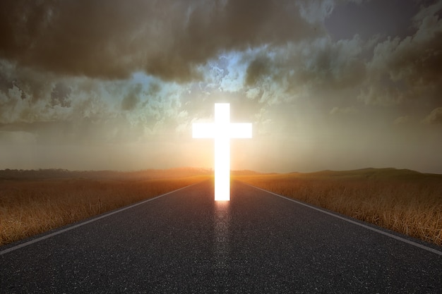 Christian cross at the end of the road with sunlight background