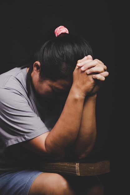 Christian woman hand on holy bible are pray and worship for thank god in church with black background concept for faith spirituality and religion