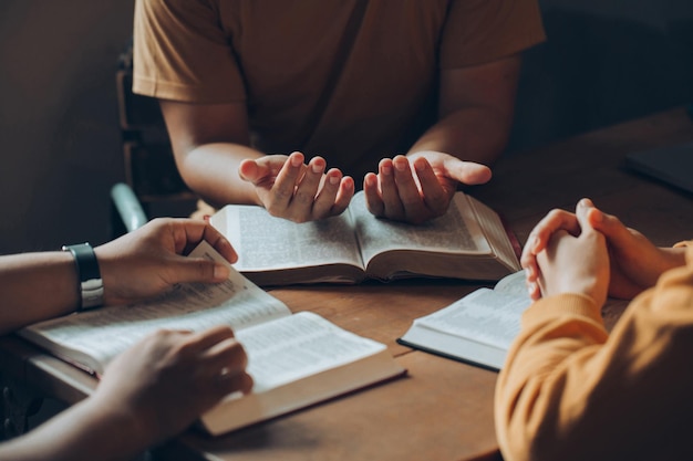 Christians and Bible study concept Christi family sitting around a wooden table with open bible