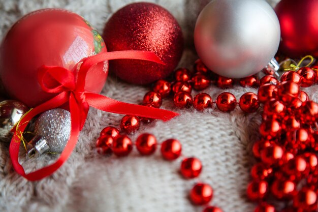 Christmas adornment and festive holiday decor. red glittery embellishment assortment. balls and bead string on the knit textured fabric.