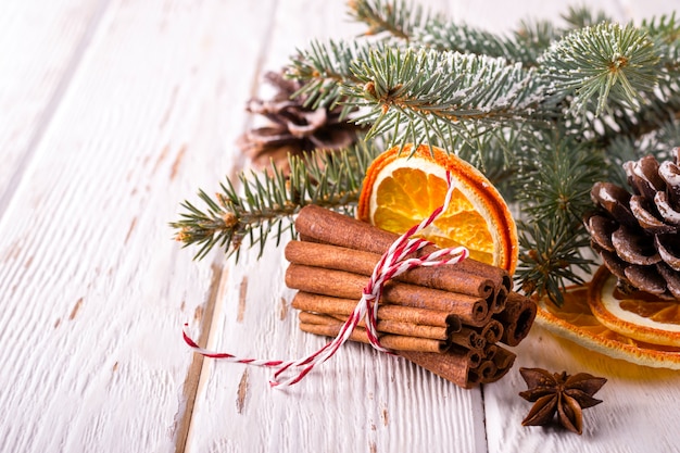 Christmas atmosphere composition with cinnamon and dry oranges on white wooden background