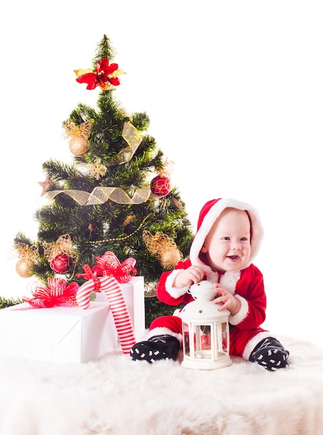 Christmas baby under the New Years tree with gifts