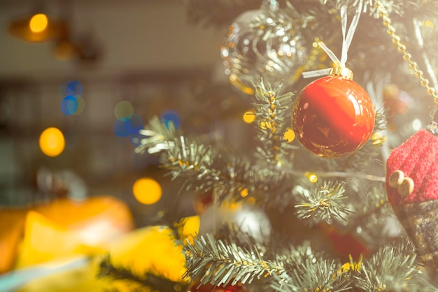 Christmas background baubles and branch of spruce treeShiny Christmas red ball hanging on pine branches with festive backgroundCloseup of red bauble hanging from a decorated Christmas tree