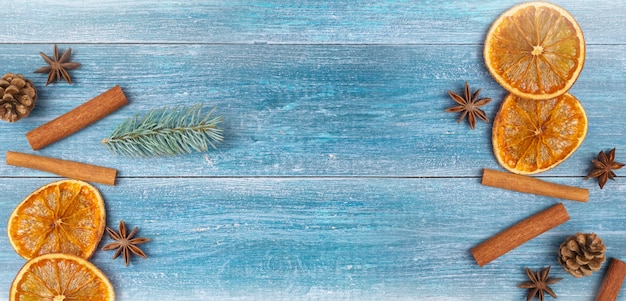 Christmas background: dried oranges, anise stars, cinnamon sticks, sprig of spruce, on a blue wooden background