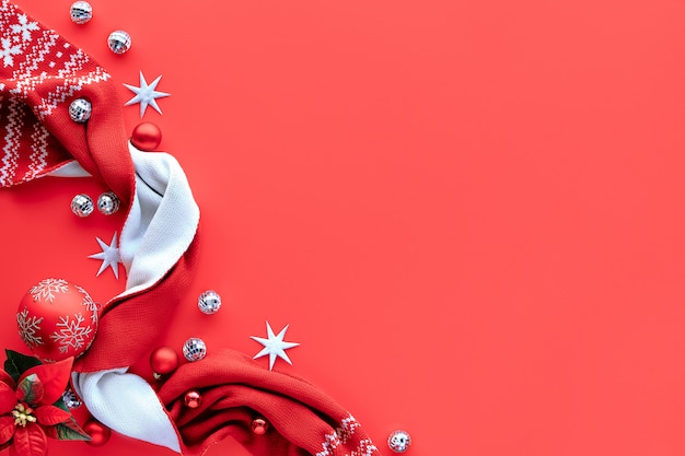 Christmas background, flat lay with white and red decorations on coral red background, place for text. Scarf, disco balls, baubles.