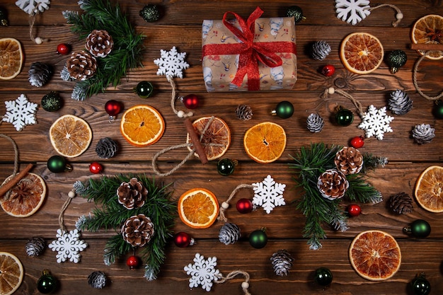 Christmas background Gift in vintage packaging dried oranges Christmas toys and branches Christmas decor on a wooden table