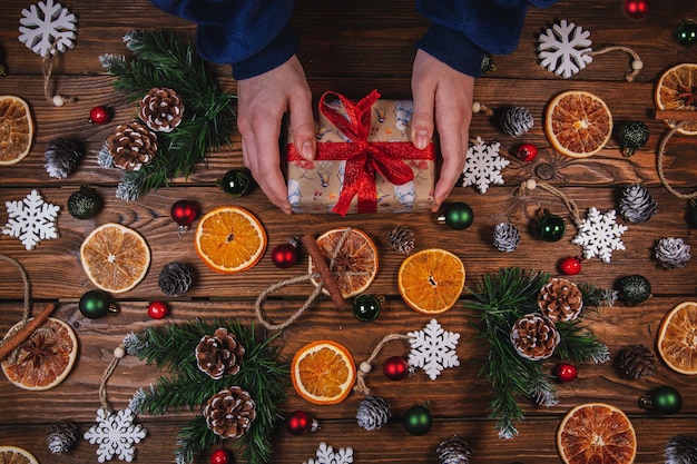 Christmas background Gift in vintage packaging dried oranges Christmas toys and branches Christmas decor on a wooden table