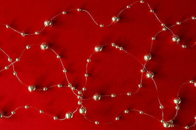 Christmas background Gold beads lie on a red paper background