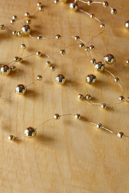 Christmas background Gold beads on a light yellow wooden background