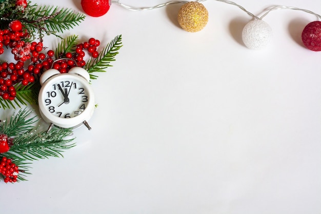 Christmas background, spruce twigs with red berries, clock and garland with balloons on a white background, flat lay, copy space