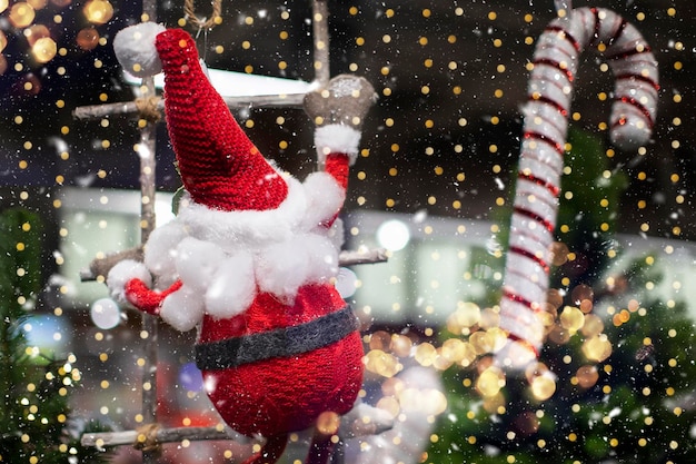 On a Christmas background a toy santa claus climbs a rope ladder