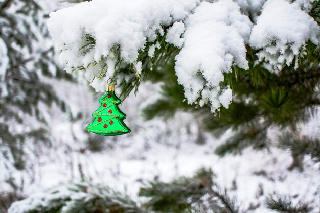 Christmas background with a Christmas toy on a snowy pine branch with a copy space