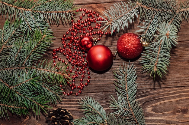 Christmas background with fir sprig and red toys on wooden boards.