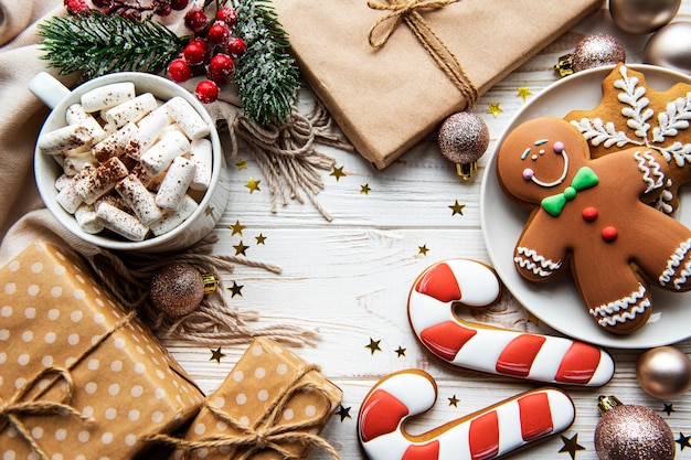 Christmas background with gift box, cocoa and gingerbread cookies. White wooden background.