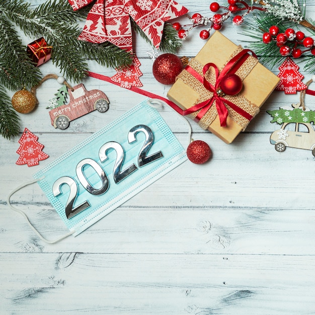 christmas background with new year decorations medical mask with numbers 2022 on wooden background