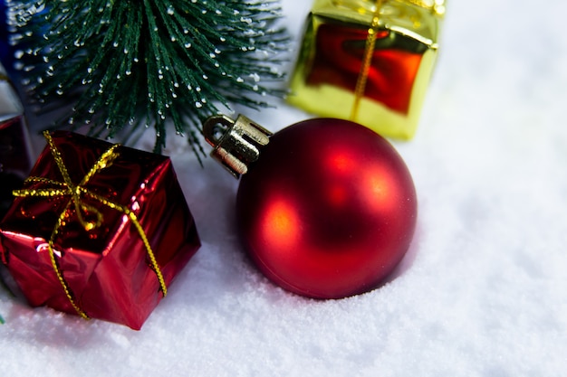 Christmas background with a red ball and, golden gift in snow