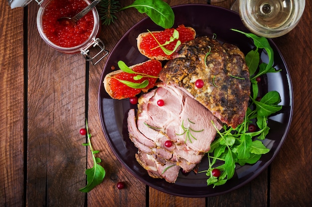 Christmas baked ham and red caviar, served on the old wooden table.