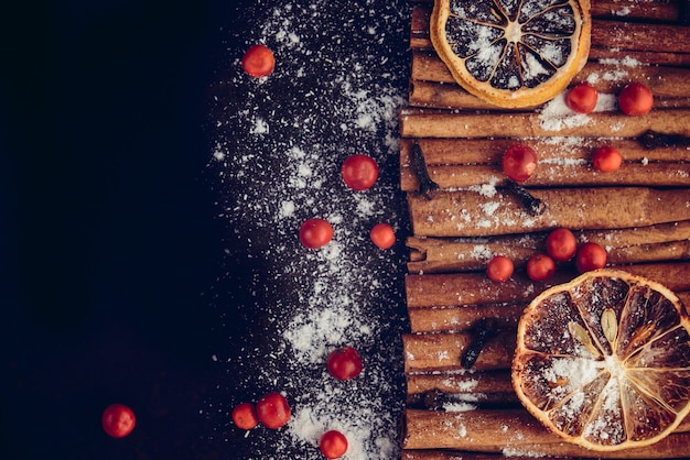 Christmas bakery and New Year concept. Holiday background with dried lemon citrus slices, set of cinnamon sticks and vanilla powder. Cosy winter holiday baking, mulled wine frame on dark background. 