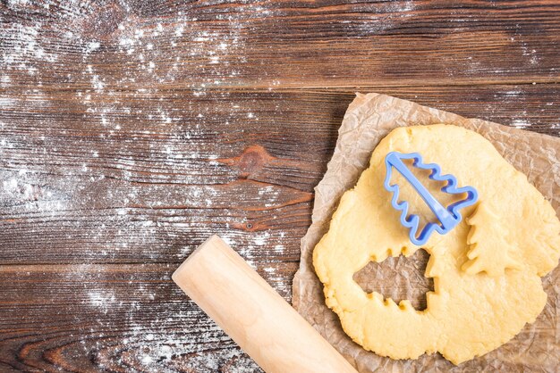 Christmas baking of ginger cookies on dark wooden background with fir branches.