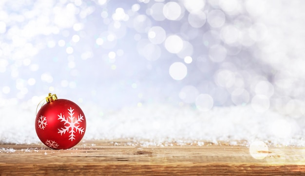 Christmas ball on a wooden desk snowy bokeh background