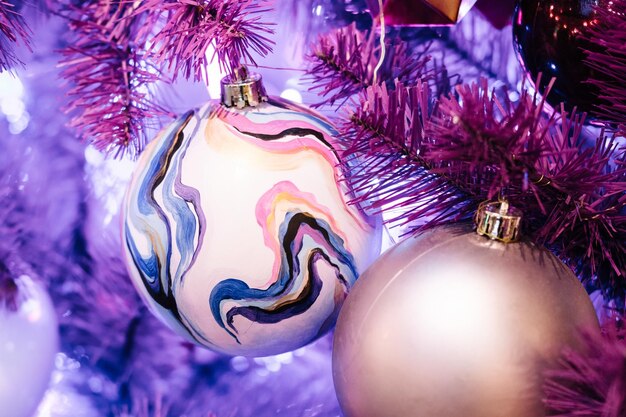 Christmas balls and glowing garlands on a purple christmas tree