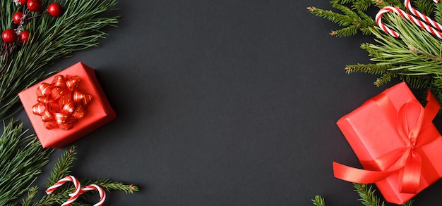 Christmas banner made of red presents decoration and tree branches on black background new year