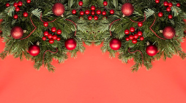 Christmas banner with spruce branches and red bead on the red background Copy space