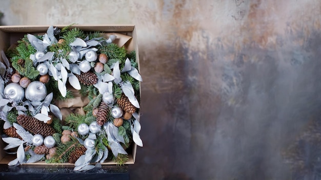 Christmas banner with wreath with natural elements, silver apples and leaves. Green and silver Christmas wreath on a brown grunge background