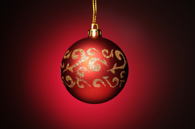 Christmas bauble with gold decoration on red background