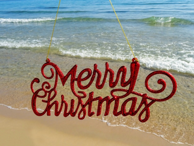 Christmas at the beach. Merry Xmas sign in front of the sea.