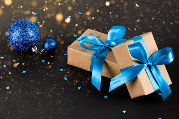 on a christmas black background gifts with a blue ribbon and balls with bokeh