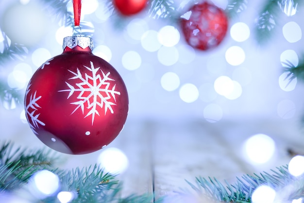 Christmas bokeh background with pine branches and red ornate ball.