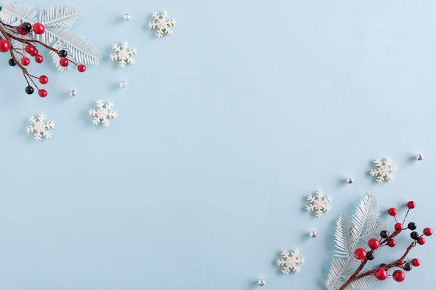 Christmas border made of snowflakes and red berries on blue surface