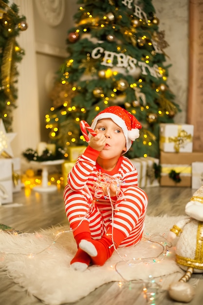 Christmas boy with red candy cane and santa hat