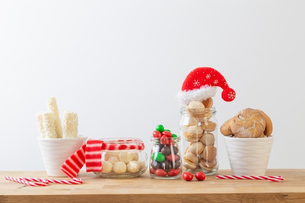 christmas candies and cookies in jars on wooden shelf on white background