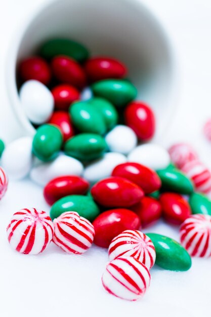 Christmas candies spilled out of the cup on white background.