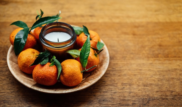 Christmas candles for festive season citrus candle and juicy oranges on kitchen wooden table new