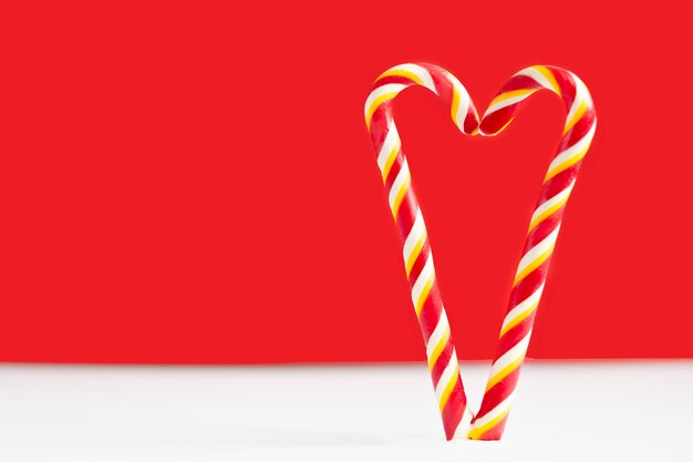 Christmas candy canes on a red background Heart on a red background Heart made of lollipops Heart for valentine's day