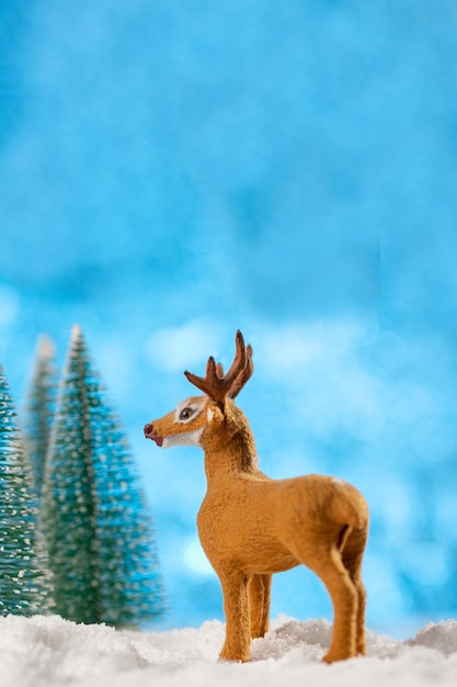 Christmas card conception. Christmas toy deer decoration with christmas trees and snow