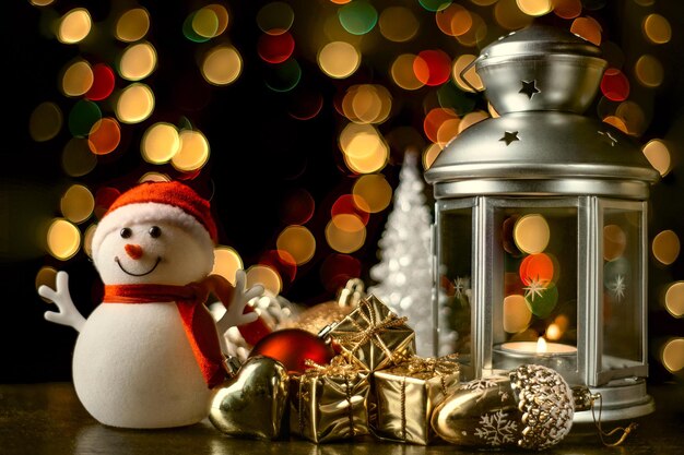 Christmas card a snowman a lantern with candles bright shiny boxes with gifts and blurry lights