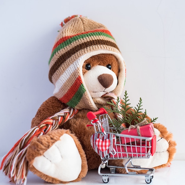 Christmas card with Teddy Bear and Christmas gifts in supermarket trolley.