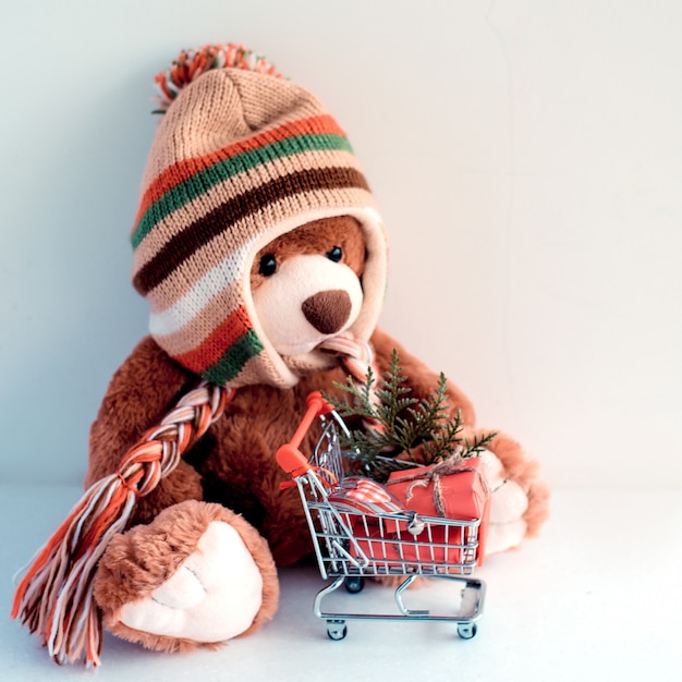 Christmas card with Teddy Bear and Christmas gifts in supermarket trolley 