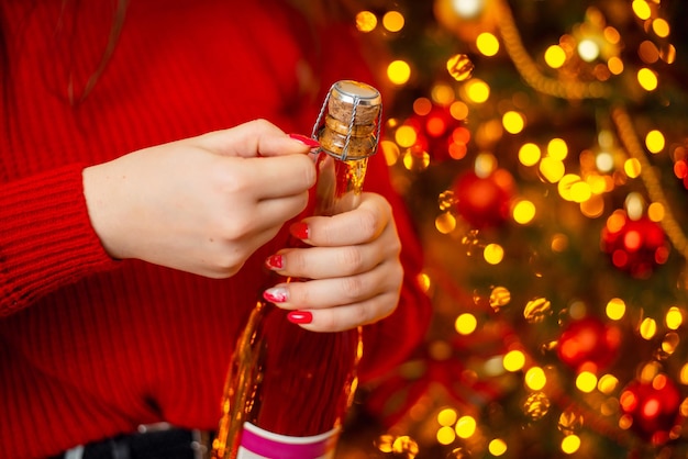 Christmas celebration concept Closeup shot of hands of a girl opening bottle with champagne