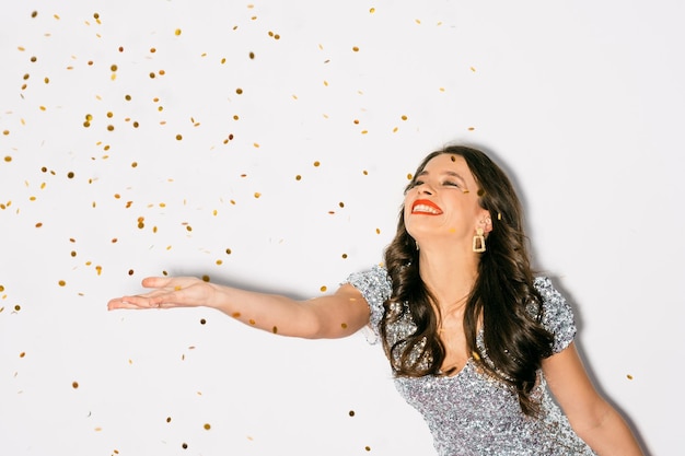 Christmas celebration Excited woman Festive decor Happy beautiful lady enjoying party throwing sparkle golden confetti spangles isolated white copy space