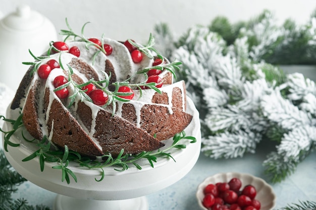 Christmas chocolate bundt cake Traditional Christmas fruit cake with white glaze cranberries and rosemary on white stand with Christmas decoration Winter baking at Xmas or New Year Copy space