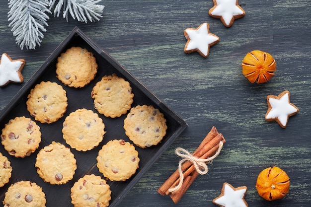 Christmas chocolate chip cookies, flat lay with spices and winter decorations on dark