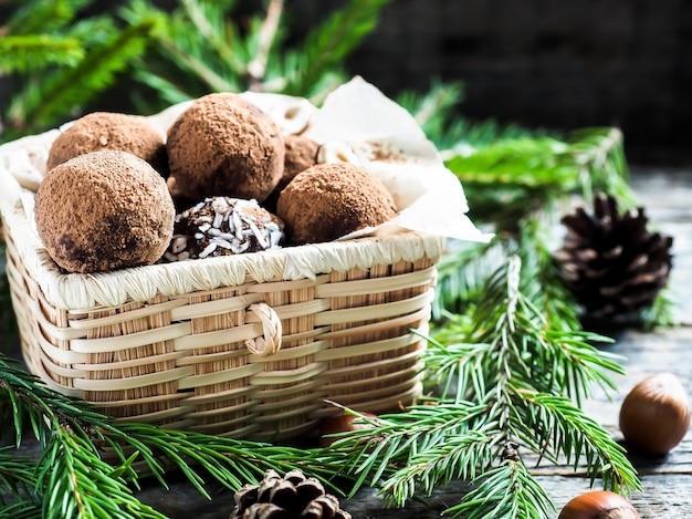 Christmas chocolate truffles in a wicker box the fir tree branches on wooden table